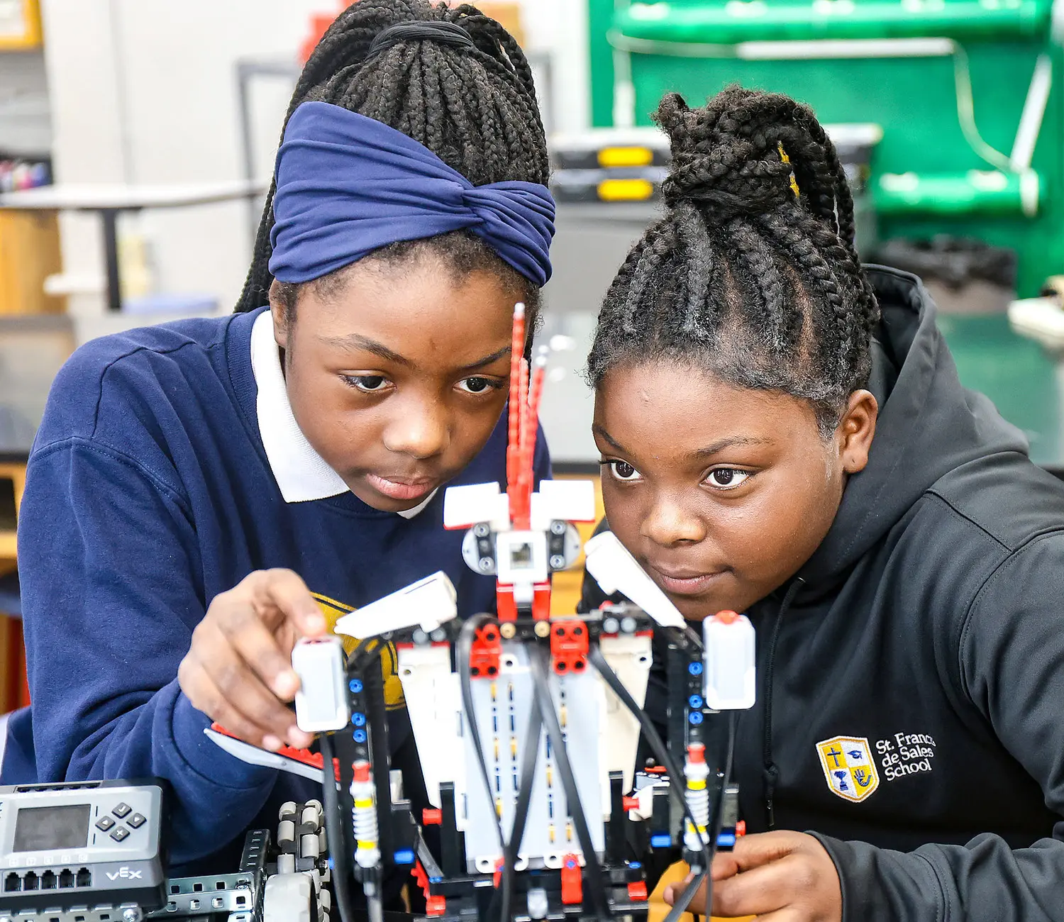 Two female students focusing on building robot