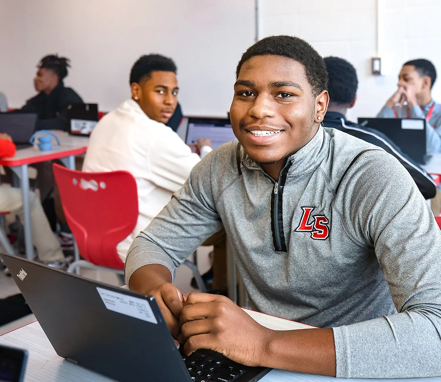 Male student sitting at desk with computer smiling