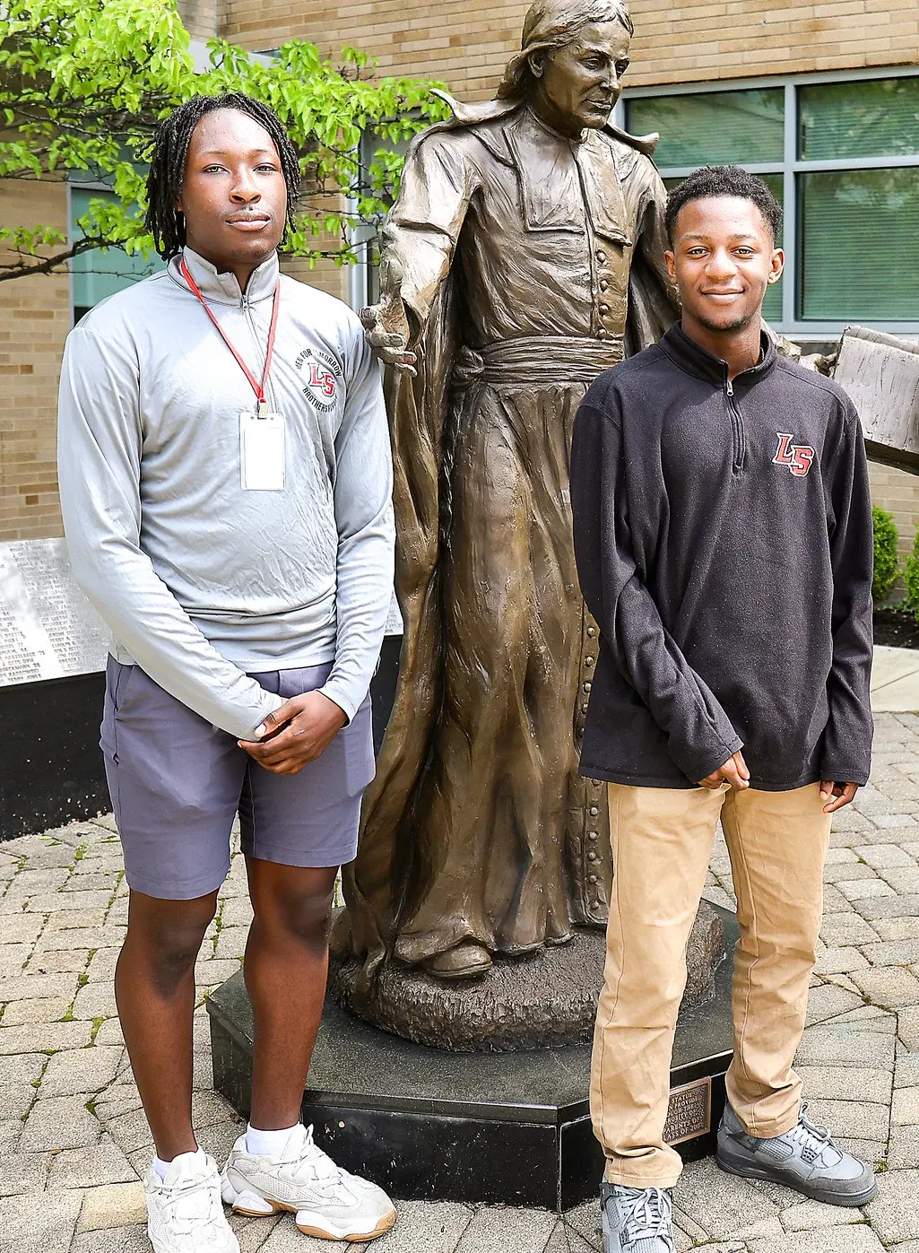 Two high school students standing next to statue