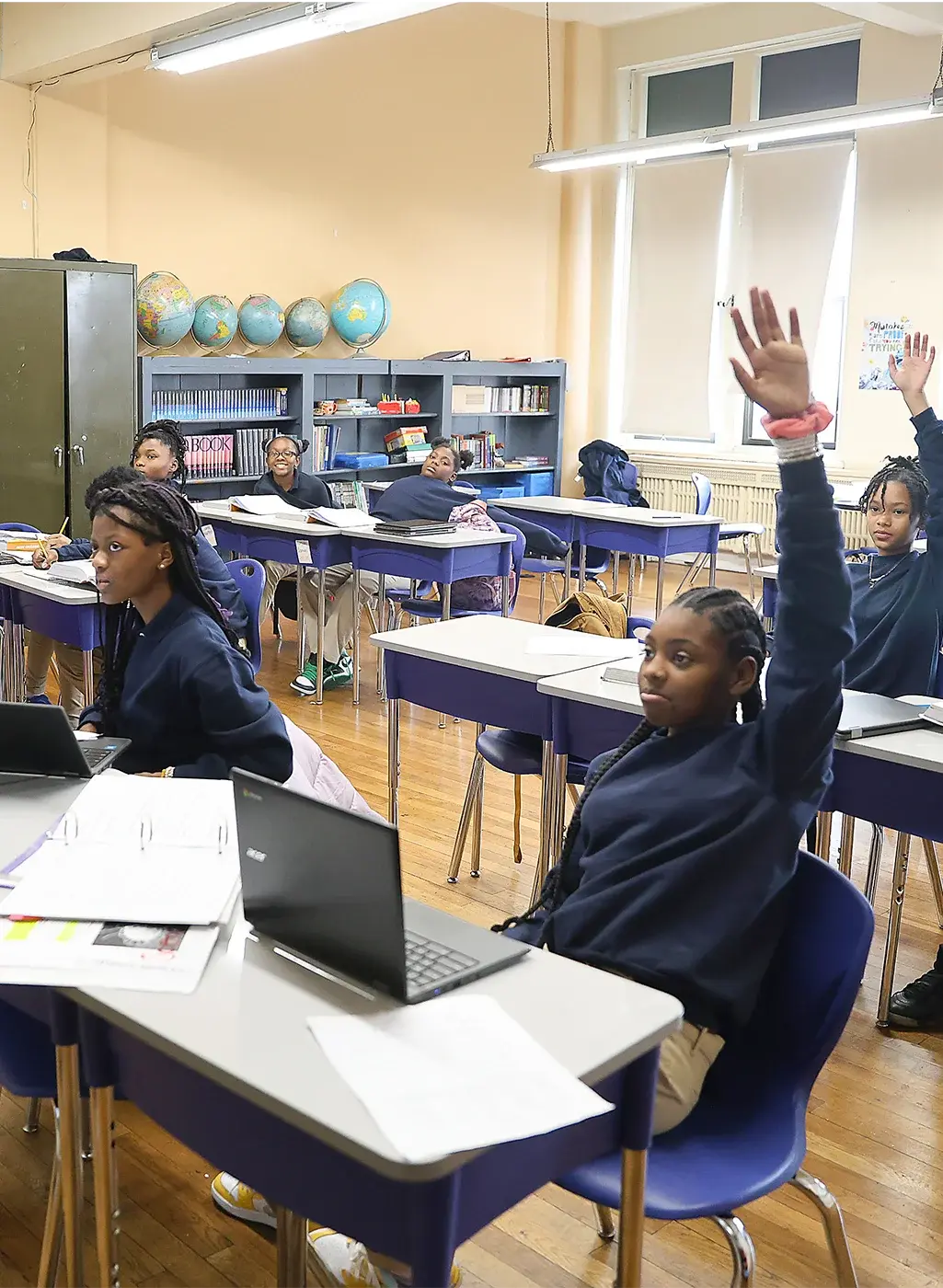 Students sitting in classroom raising hands