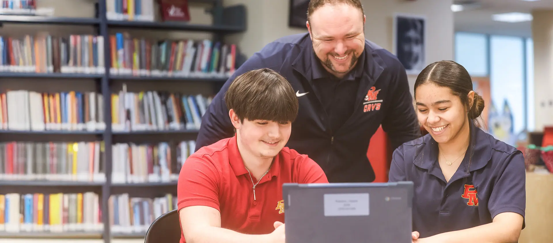 two highschool students with teacher looking at computer