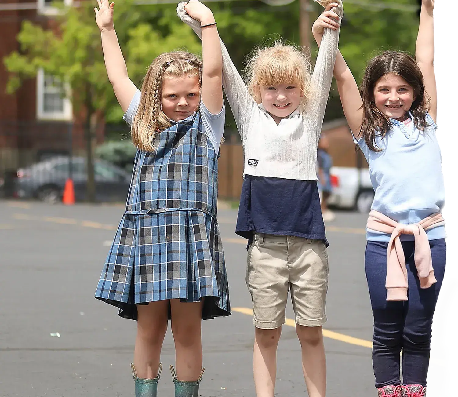 Three girls standing outside with hands interlinked above heads